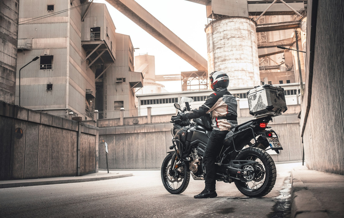 Piloto equipado junto a moto adventure con valijas